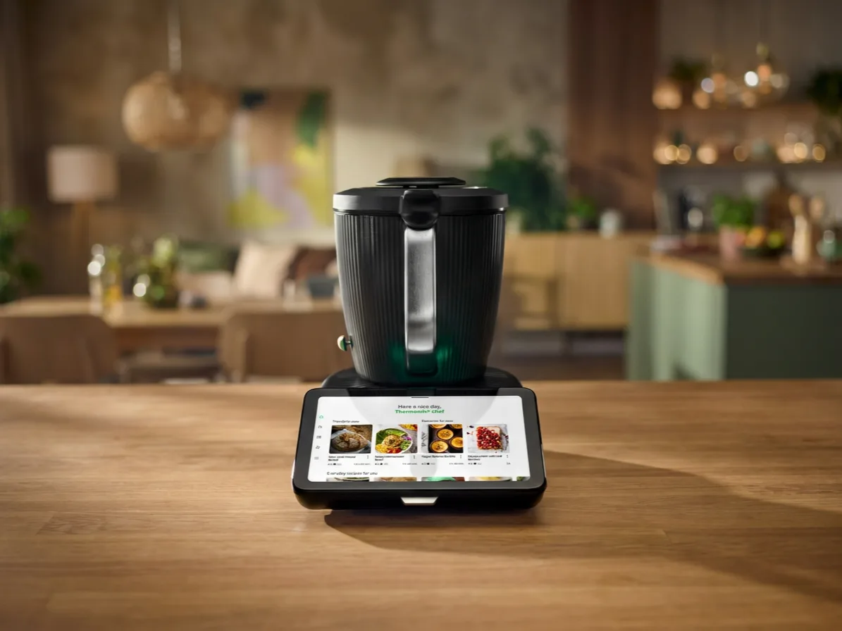 Thermomix TM7 mit Touchscreen auf einem Holztisch, formatfüllend mit erweitertem Hintergrund